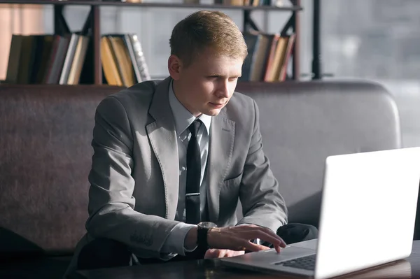 İşadamı dizüstü bilgisayarla masada oturuyor.