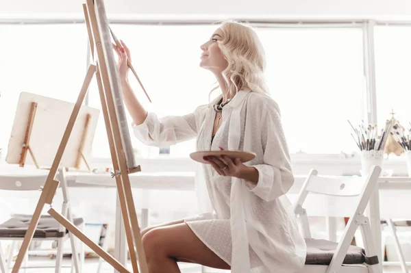 Bir kadın bir resim şövale üzerinde çizer.