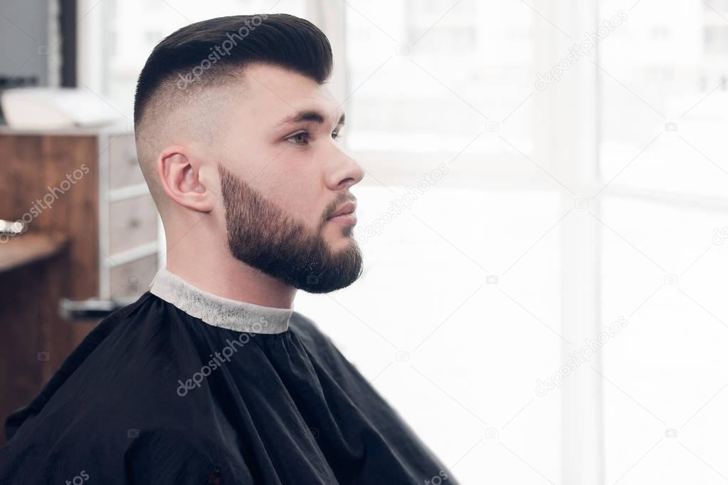 a young guy sitting on a chair in the barbershop