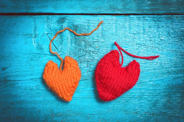 Colorful knitted hearts on the blue boards