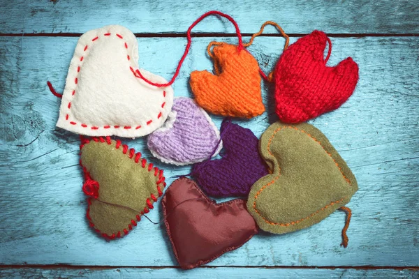 Colorful knitted hearts on the light blue boards