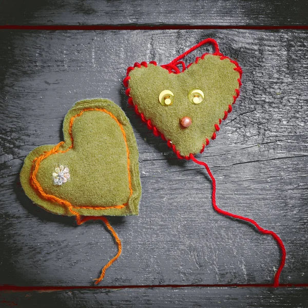 Colorful knitted hearts on the dark boards — Stock Photo, Image