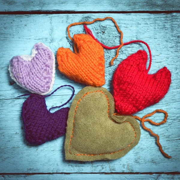 Colorful knitted hearts on the light blue boards — Stock Photo, Image