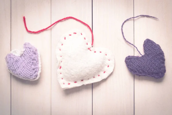 Colorful knitted hearts on light, wooden boards — Stock Photo, Image