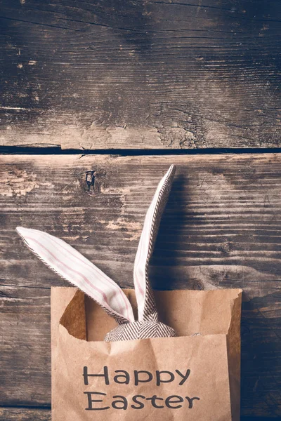 Lapin de Pâques dans un sac en papier sur de vieux planches — Photo
