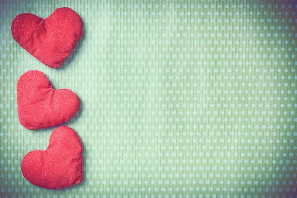 Colorful knitted hearts on a green background