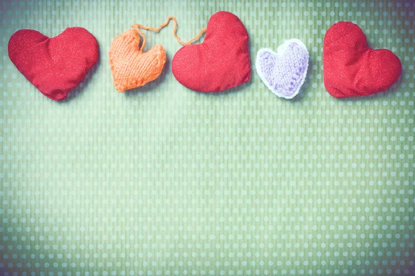Colorful knitted hearts on a green background — Stock Photo, Image