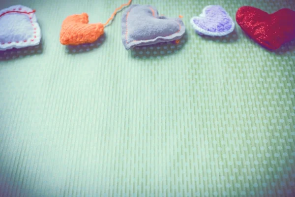 Colorful knitted hearts on a green background