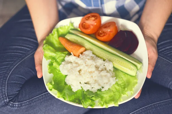 Una ragazza tiene un piatto con riso e verdure — Foto Stock