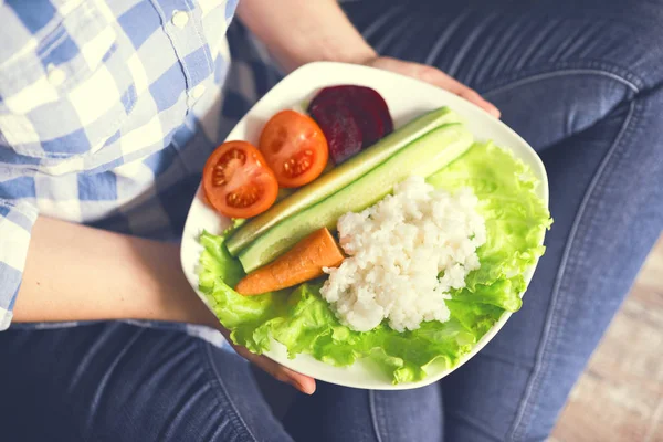 Una ragazza tiene un piatto con riso e verdure — Foto Stock