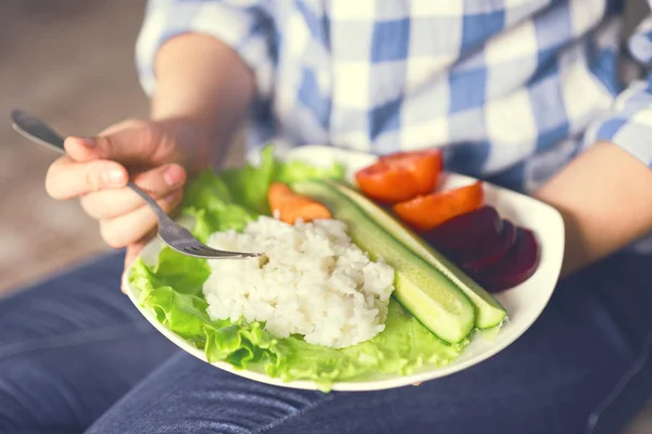 Una ragazza tiene un piatto con riso e verdure — Foto Stock