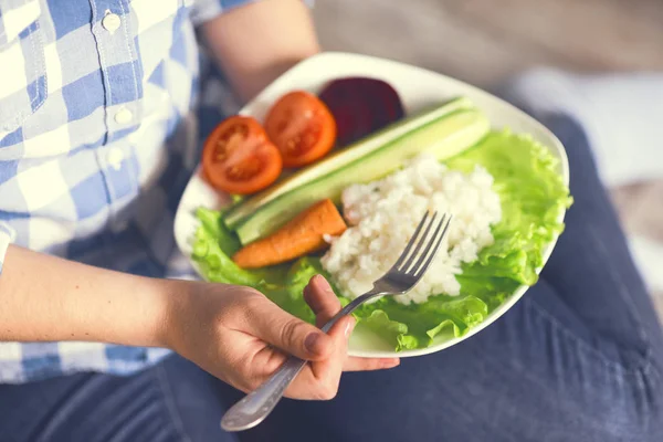 A girl holds a plate with rice and vegetables — Stock Photo, Image