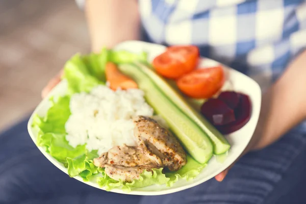 Una ragazza tiene un piatto con verdure e carne di pollo con spezie . — Foto Stock