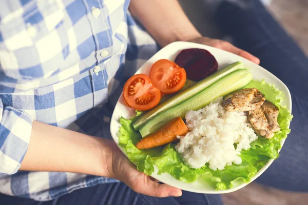 Una ragazza tiene un piatto con verdure e carne di pollo con spezie . — Foto Stock