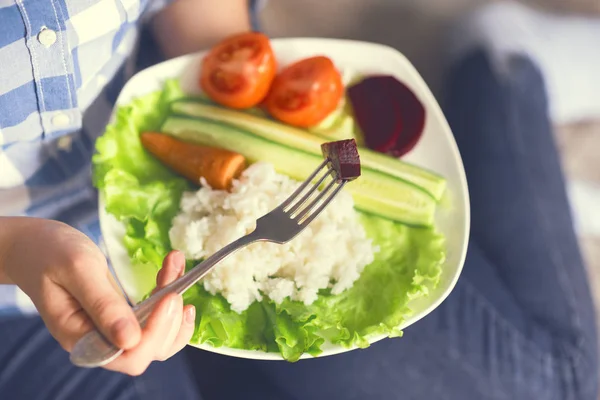 Una ragazza tiene un piatto con riso e verdure — Foto Stock