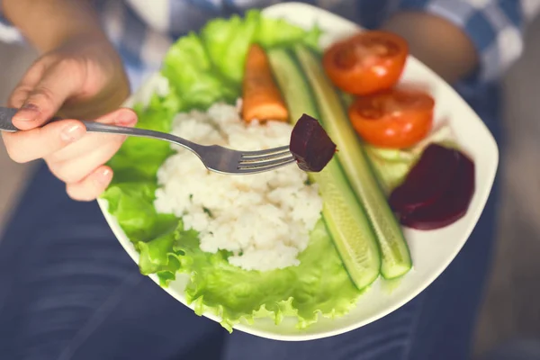 Una ragazza tiene un piatto con riso e verdure — Foto Stock