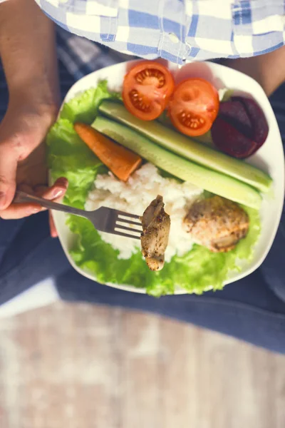 Una ragazza tiene un piatto con verdure e carne di pollo con spezie . — Foto Stock
