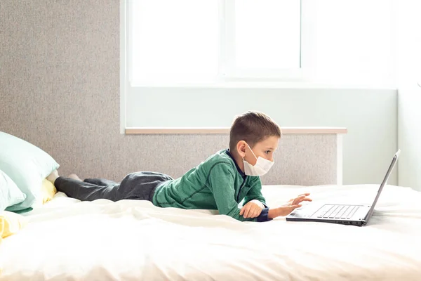 待在家里检疫大肠癌大流行预防 一个孩子在隔离期间通过笔记本电脑在网上学习 远程学习 预防流行病 Covid 图库图片