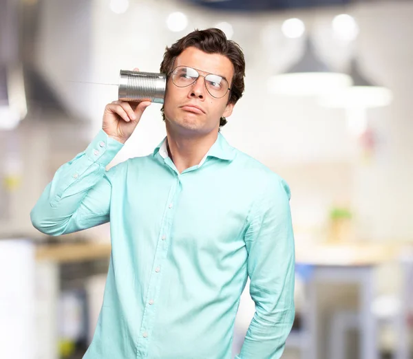 Jovem confuso com telefone de latas — Fotografia de Stock