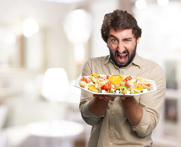 Angry young man with salad — Stock Photo, Image