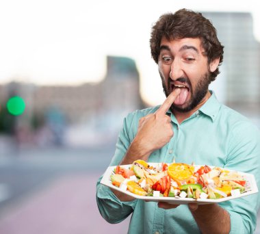 kusmuk işareti ve salata ile genç adam