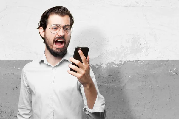 Vihainen nuori mies matkapuhelimen kanssa — kuvapankkivalokuva