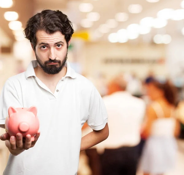 Sad young man with piggy bank — Stock Photo, Image