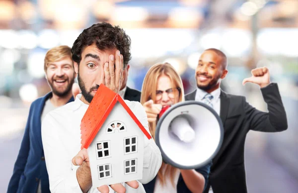Man with a house model and surprise expression — Stock Photo, Image