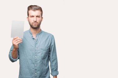 Mavi kot gömlek giymiş bir afiş tutarak yakışıklı delikanlı. Tek renkli arka planı izole kişi.