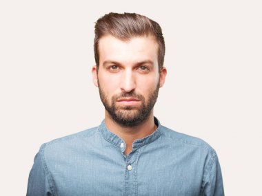 Bir mavi t gömlek giymiş yakışıklı delikanlı. Tek renkli arka planı izole kişi.