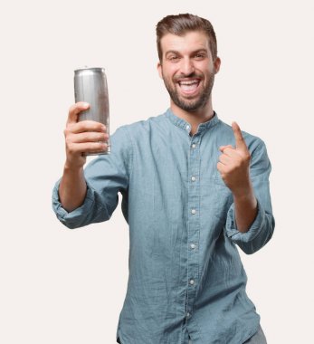 Genç yakışıklı adam, mavi kot gömlek, bir bira bira bardağı tutan, dans veya ifade kutluyor. Tek renkli arka planı izole kişi.