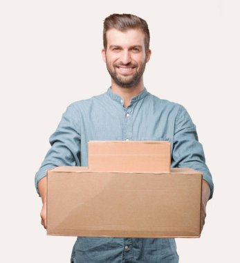 Genç yakışıklı adam, mavi kot gömlek, bir paket tutmak. Mutlu ifade. Tek renkli arka planı izole kişi.