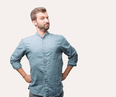 Genç yakışıklı adam, mavi kot gömlek, bir meydan okuma ve gurur ifadesi karşı karşıya. Tek renkli arka planı izole kişi.