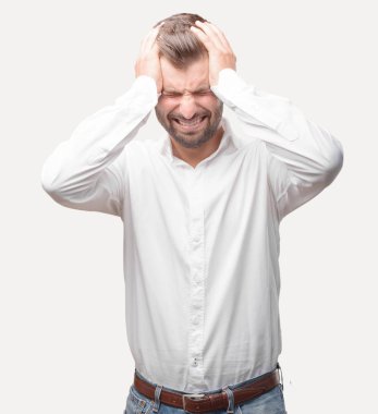 Üzgün ifade beyaz t gömlek giymiş genç yakışıklı adamla poz depresif. Tek renkli arka planı izole kişi.