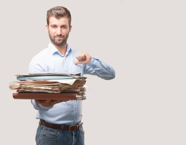 Bir kule, belgeleri veya dosyaları giyen bir mavi tişörtlü, gurur ifadesi tutan yakışıklı delikanlı. Tek renkli arka planı izole kişi.