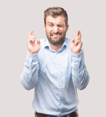 Yakışıklı delikanlı parmak geçiş bir mavi t gömlek giymiş ifade korkuyor. Tek renkli arka planı izole kişi.