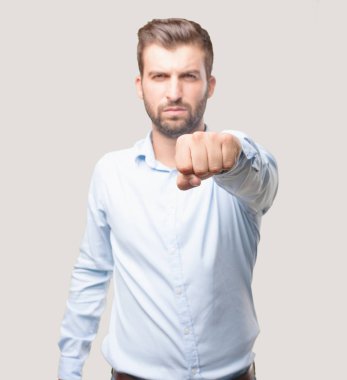 Bir mavi t gömlek giymiş yumruk gösterilen yakışıklı delikanlı. Tek renkli arka planı izole kişi.