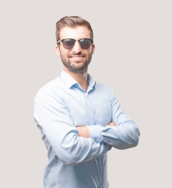 Bununla birlikte güneş gözlüklü bir mavi t gömlek giymiş genç yakışıklı adam. Mutlu ifade. Tek renkli arka planı izole kişi.