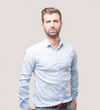 Yakışıklı delikanlı ile gurur ya da mutlu ifade bir mavi t gömlek giymiş. Tek renkli arka planı izole kişi.
