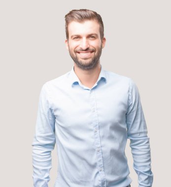 Yakışıklı delikanlı ile gurur ya da mutlu ifade bir mavi t gömlek giymiş. Tek renkli arka planı izole kişi.
