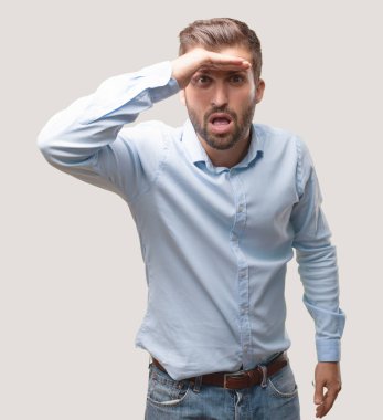 genç yakışıklı adam arıyorum far poz mavi t gömlek giymiş. Tek renkli arka planı izole kişi.