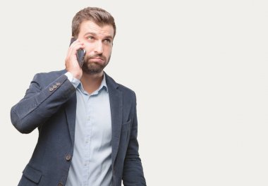 Genç yakışıklı işadamı bir smartphone giyiyor mavi ceket ile sıkılmış ifade konuşma. Tek renkli arka planı izole kişi.