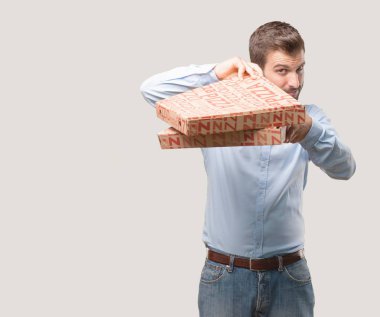 yakışıklı delikanlı pizza tutan mavi tişörtlü, mutlu ifade kutuları. tek renkli arka planı izole kişi