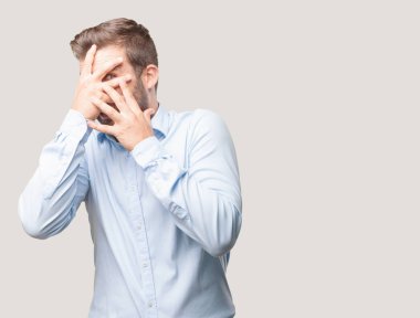 Yakışıklı delikanlı, mavi tişörtlü korkuttu ifade ya da korkmuş. Bir şey hakkında endişeli. Tek renkli arka planı izole kişi.