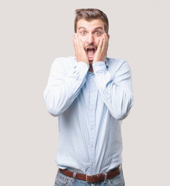 Mutlu ve yakışıklı delikanlı, mavi t gömlek ve sürpriz ifade. Tek renkli arka planı izole kişi.