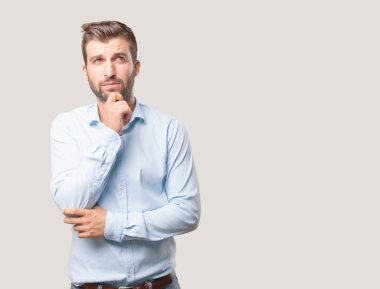 Karışık ve yakışıklı delikanlı, mavi t gömlek, düşünce ya da endişeli ifade. Tek renkli arka planı izole kişi.