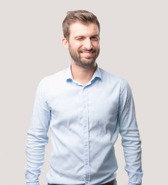 genç yakışıklı kırpan göz poz mavi t gömlek giymiş adam. Tek renkli arka planı izole kişi.