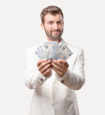 Genç yakışıklı işadamı 20 euro banknot, beyaz ceket, mutlu ifade. Tek renkli arka planı izole kişi.