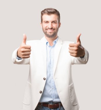 Tüm doğru ya da Tamam işareti, beyaz ceket ve mutlu ifade ile genç yakışıklı işadamı. Tek renkli arka planı izole kişi.