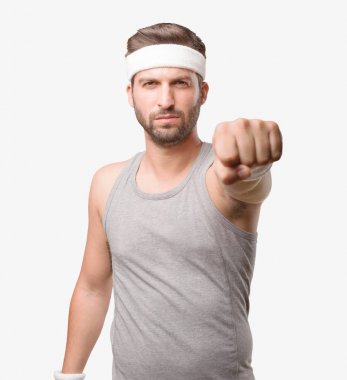 Yumruğunu gri tank top ile gösterilen genç yakışıklı sporcu. Tek renkli arka planı izole kişi.